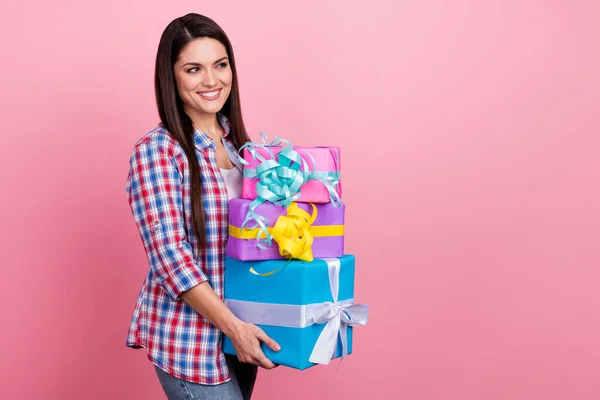 Foto de mujer bastante dulce usar camisa a cuadros sosteniendo regalos buscando espacio vacío aislado color rosa fondo —  Fotos de Stock