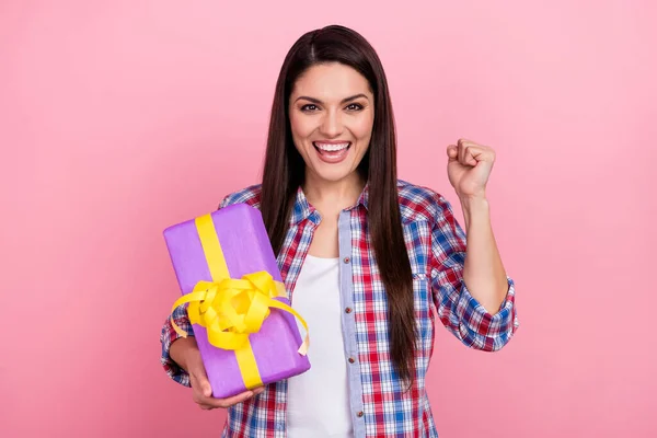 Photo of sweet lucky woman wear plaid shirt holding present rising fist isolated pink color background — Foto de Stock