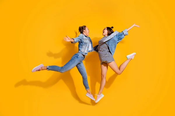 Full length of two overjoyed people jumping raise opened hands hug isolated on yellow color background — Zdjęcie stockowe