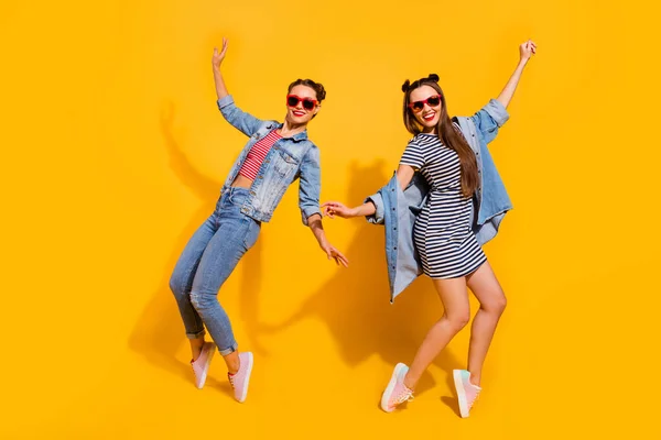 Teljes hosszúságú portré két boldog aktív hölgyek élvezik tánc klubok elszigetelt sárga színű háttér — Stock Fotó