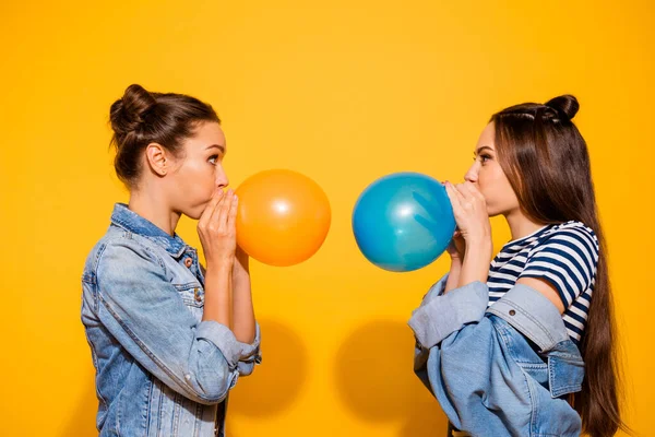 Profile photo of two funky positive people blowing balloon look each other isolated on yellow color background — Zdjęcie stockowe