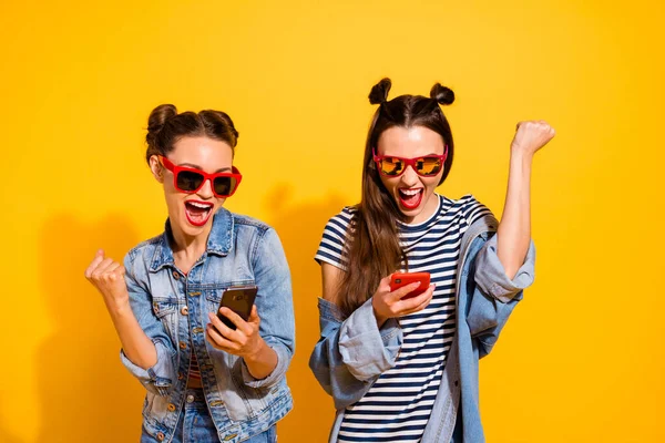 Photo of delighted overjoyed girls blogging raise fist celebrate like subscribe isolated on yellow color background — Stockfoto