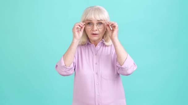Aged lady worker choose new optics specs isolated cyan color background — Vídeo de Stock