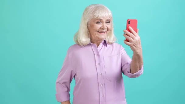 Senhora idosa blogging responder chamada virtual gadget isolado cor ciano fundo — Vídeo de Stock