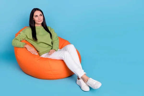 Full length photo of pretty calm girl sit big soft chair look interested empty space isolated on blue color background — Zdjęcie stockowe
