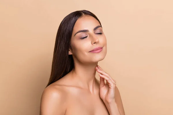 Portrait of attractive dreamy girl touching flawless clean skin enjoying facial isolated over beige pastel color background —  Fotos de Stock