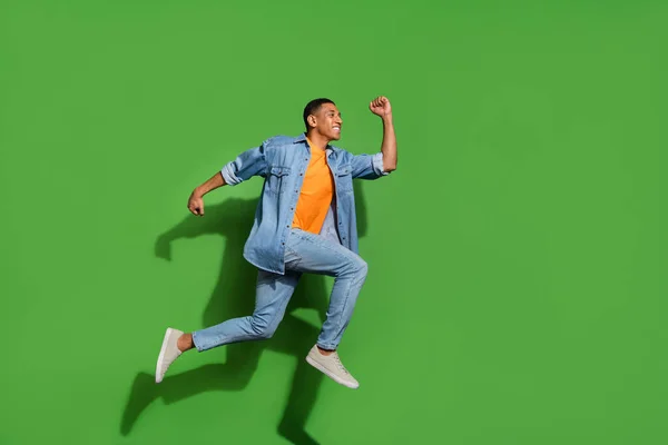 Full tělo foto energické aktivní mladý pohledný student věk muž běží ve vzduchu izolované na zeleném pozadí — Stock fotografie