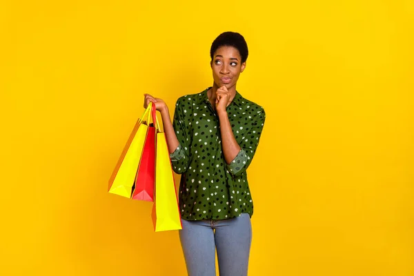 Photo of dreamy unsure trans human wear smart casual clothes holding bargains looking empty space isolated yellow color background — Foto de Stock