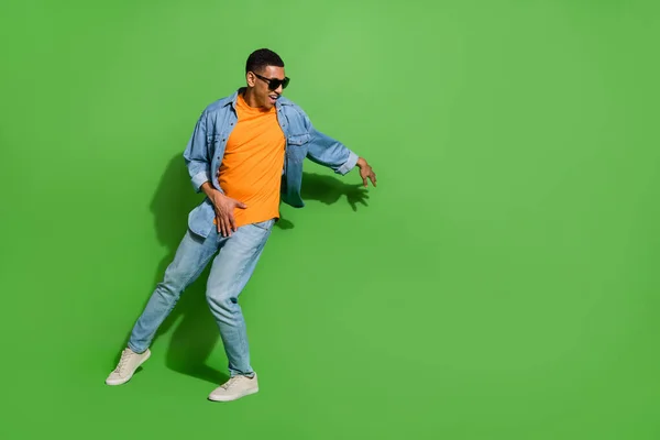 Imagen completa de buen humor masculino joven en gafas de sol bailando en discoteca aislado sobre fondo de color verde — Foto de Stock