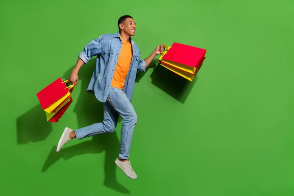 Full body profile side photo of handsome young guy go shopping during black friday isolated on green color background — Zdjęcie stockowe