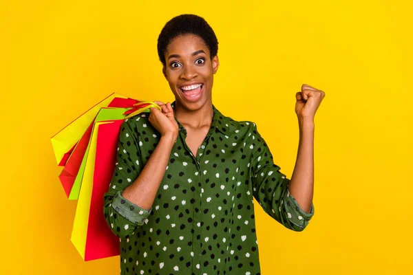 Photo of lucky excited trans human wear smart casual clothes holding bargains rising fist isolated yellow color background — Stok fotoğraf