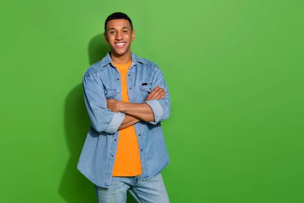 Photo of young handsome cheerful male with crossed arms wear cool denim clothes isolated on green color background — Stockfoto