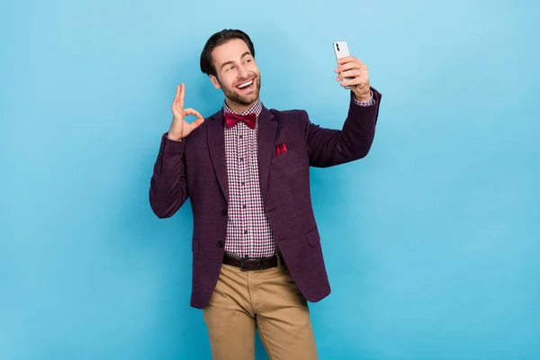 Photo of young guy make take selfie video recording show fingers okey symbol choice promo isolated over blue color background — Stockfoto