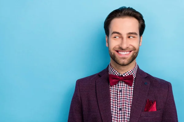 Portrait of cheerful thoughtful showman in tuxedo look empty space see promotion isolated on blue color background – stockfoto