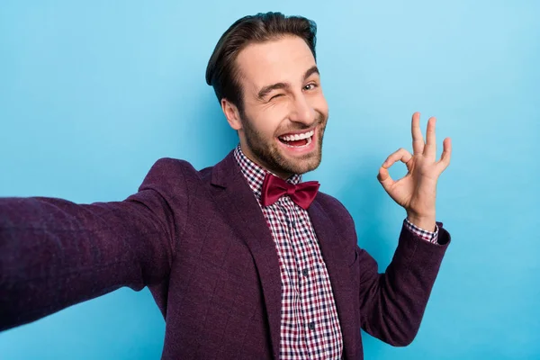 Photo of young excited guy wink eye show fingers okey symbol feedback perfect take selfie isolated over blue color background — Φωτογραφία Αρχείου