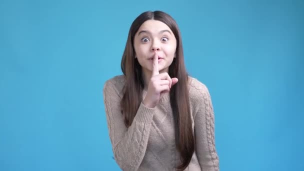 Мрійлива леді-підліток просить не ділитися неймовірною таємницею ізольованого синього кольору фону — стокове відео