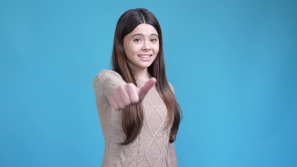 Tenåringsdamen velger å gjøre tommelen nedover, ikke som isolert blå farge bakgrunn – stockvideo