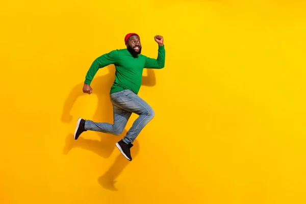 Photo of sporty energetic active guy jump rush side empty space wear red beanie green shirt isolated yellow color background —  Fotos de Stock