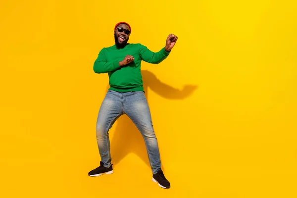 Photo of excited positive man dance crazy funny moves wear sunglass red beanie green shirt isolated yellow color background — Stockfoto