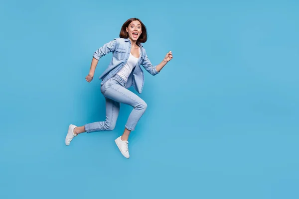 Photo of pretty excited woman wear jeans shirt hurrying jumping high isolated blue color background — Fotografia de Stock