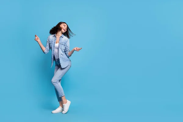 Photo of excited pretty lady dressed denim shirt looking empty space dancing isolated blue color background — Stockfoto