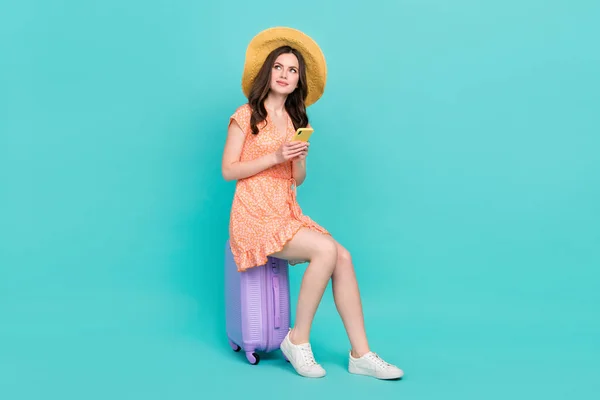 Photo of cute thoughtful woman wear orange outfit panama booking travel app device empty space isolated turquoise color background — Fotografia de Stock