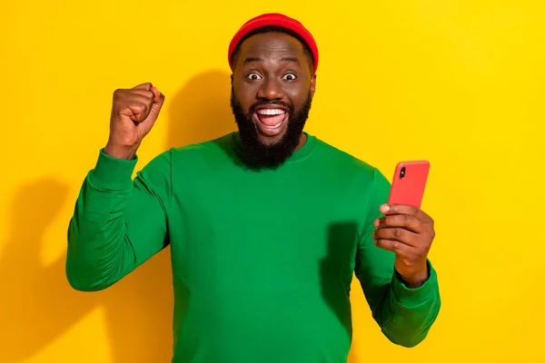 Portrait of attractive lucky cheerful guy using gadget rejoicing like post smm isolated over bright yellow color background — Stok fotoğraf