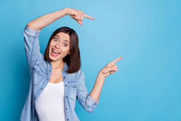 Photo of cute impressed lady dressed denim shirt pointing fingers empty space isolated blue color background — Fotografia de Stock