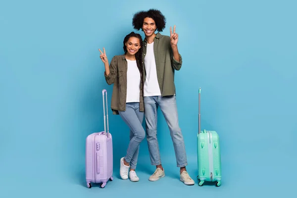Photo of friends wife husband low-cost luggage travel honeymoon make v sign wear jeans shirt isolated blue color background — Stockfoto