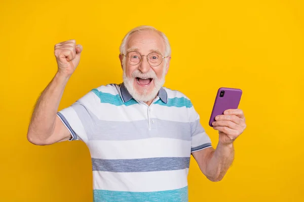 Portrait d'homme aux cheveux gris joyeux attrayant utilisant gadget célébrant post comme réaction isolée sur fond de couleur jaune vif — Photo