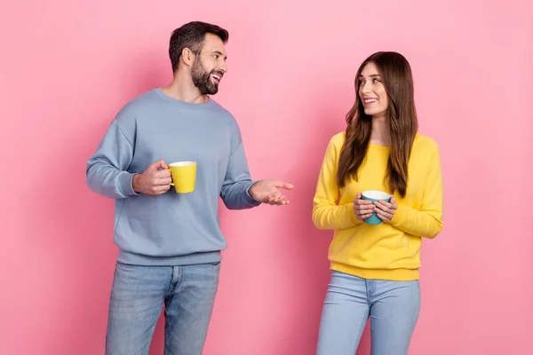 Portrait of attractive cheerful couple drinking latte cacao talking isolated over pink pastel color background — Foto Stock