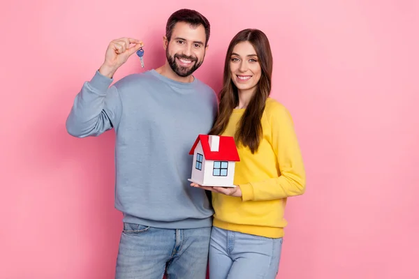 Portrait of two peaceful nice people hold showing little house key isolated on pink color background — Φωτογραφία Αρχείου