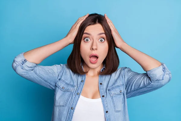 Foto van schattige geschokte vrouw dragen jeans shirt armen hoofd open mond geïsoleerde blauwe kleur achtergrond — Stockfoto