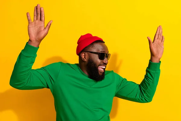 Foto von verrückt sorgenfrei fröhlichen Mann tanzen heben Palmen tragen Sonnenbrille rote Mütze grünes Hemd isoliert gelbe Farbe Hintergrund — Stockfoto