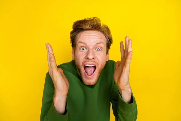 Fénykép funky lenyűgözött fickó öltözött zöld pulóver nyitott száj felemelkedő karok elszigetelt sárga háttér — Stock Fotó