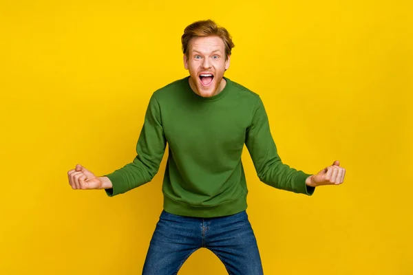 Fénykép lenyűgözött szerencsés fickó öltözött zöld pulcsi mosolygós emelkedő öklök izolált sárga színű háttér — Stock Fotó