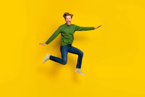 In voller Länge Foto von aufgeregt beeindruckt Mann tragen grünen Pullover springen hohe isolierte gelbe Farbe Hintergrund — Stockfoto