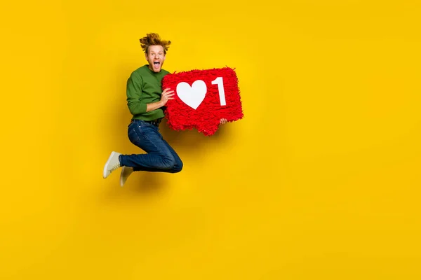 Foto de longitud completa de lindo hombre excitado usar jersey saltando corazón ascendente como piñata espacio vacío aislado color amarillo fondo —  Fotos de Stock