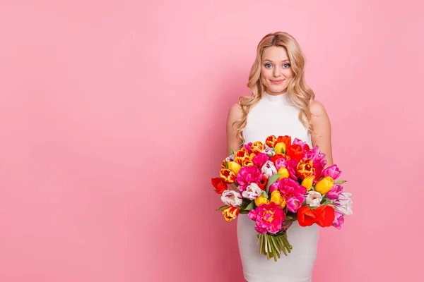 Foto de mujer positiva alegre desgaste vestido blanco conseguir flores ramo espacio vacío aislado color rosa fondo —  Fotos de Stock