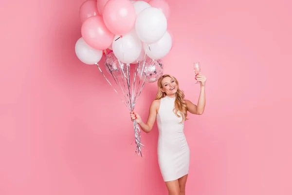 Bild av ganska trevlig flicka hålla luft ballonger champagne glas isolerad på rosa färg bakgrund — Stockfoto