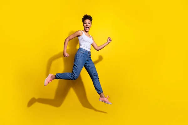 Foto em tamanho completo de energizante menina ativa pressa salto rápido isolado no fundo de cor amarela — Fotografia de Stock