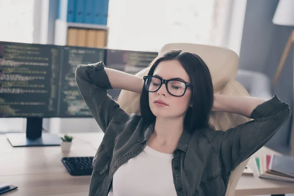 Портрет привлекательной мечтательной девушки техподдержки гик младший веб-разработчик отдыхает на стуле на рабочем месте рабочей станции в помещении — стоковое фото