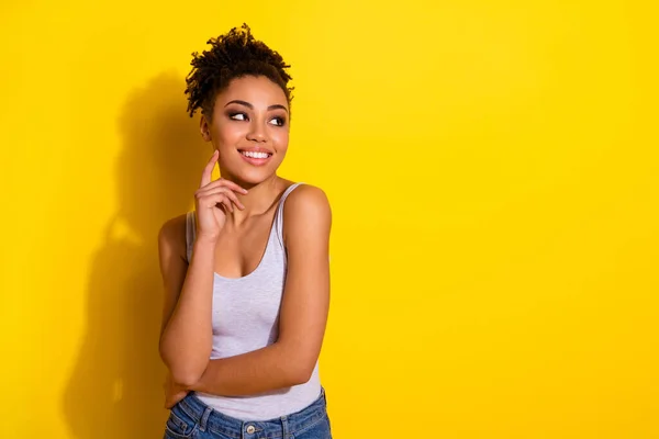 Foto de alegre hermosa persona dedo toque pómulo mirar espacio vacío aislado sobre fondo de color amarillo — Foto de Stock