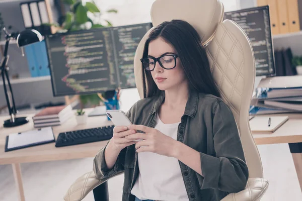 Portrett av attraktive, fokuserte, kvalifiserte jenter som sitter i stolarbeid ved hjelp av utstyr som kommuniserer på arbeidsplassen innendørs – stockfoto