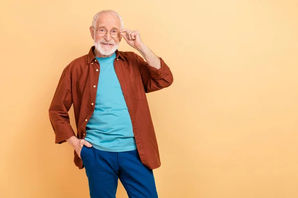 Foto de legal encantador aposentado homem cinza suéter braço óculos sorrindo espaço vazio isolado cor bege fundo — Fotografia de Stock
