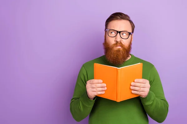 Foto de jovem homem inteligente olhando espaço em branco pensando sobre reviravoltas livro enredo isolado no fundo cor violeta — Fotografia de Stock