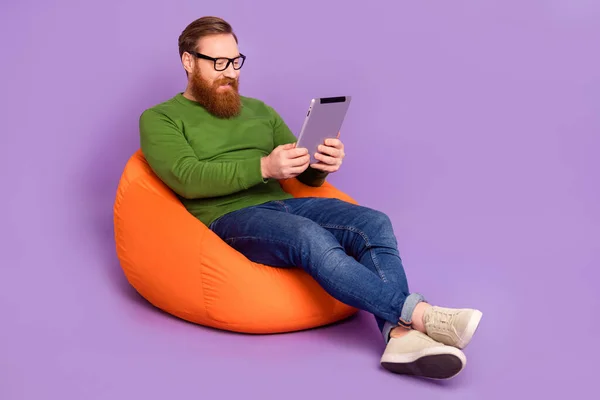 Portrait pleine longueur de la personne gaie positive assis gros sac utiliser tablette écrire email isolé sur fond de couleur pourpre — Photo