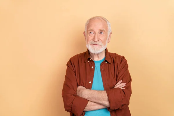 Foto de engraçado envelhecido cinza penteado homem cruzado braços olhar promo desgaste marrom roupa isolada no fundo cor bege — Fotografia de Stock