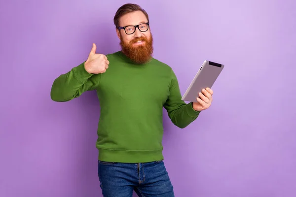 Фото привлекательного молодого фрилансера, показывающего большой палец вверх рекомендую вам новую планшетную модель, изолированную на фиолетовом фоне — стоковое фото
