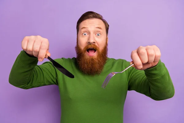 Foto di eccitato bello uomo tenere coltello forchetta mangiare posate dessert isolato su sfondo di colore viola — Foto Stock